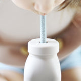 Jeune enfant, à la table, qui boit dans la paille en silicone de sa bouteille pour petit de marque Minikoioi