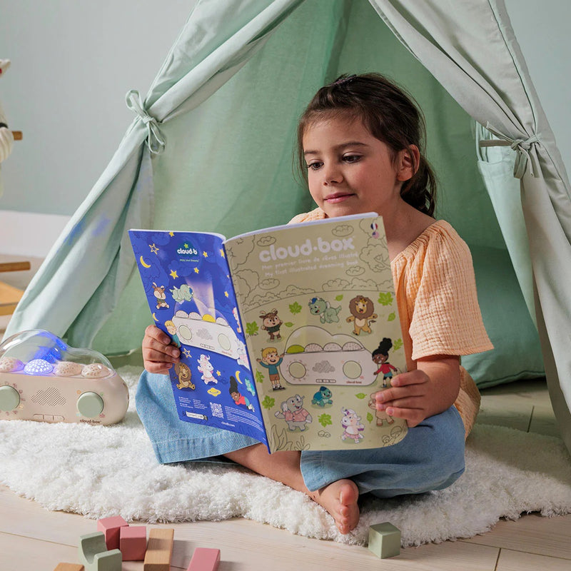 petite fille lisant son livre d'histoires illustrées qui accompagne sa première boîte à rêves de cloudb